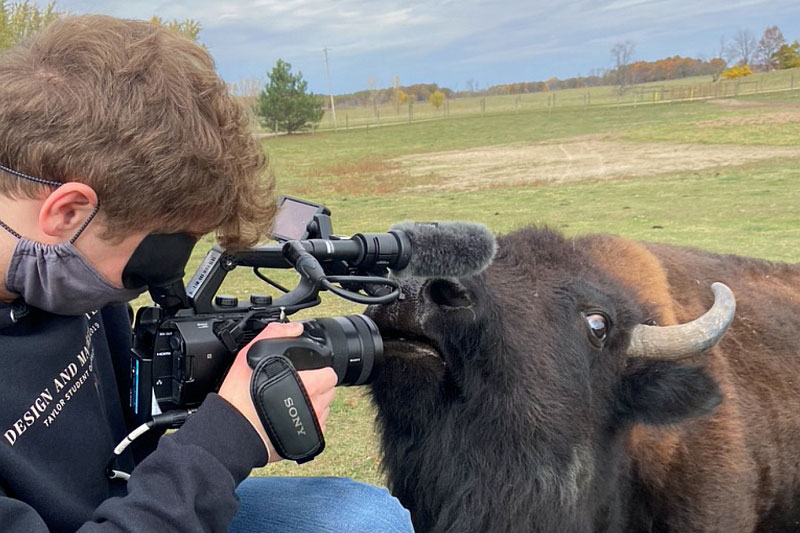 Student with a camera close to a bison