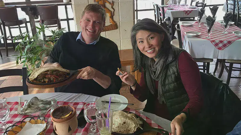 Professor May Young and Professor Hank Voss showing off the traditional food they ordered at a restaurant