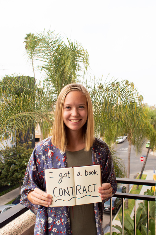 Student holding book contract sign