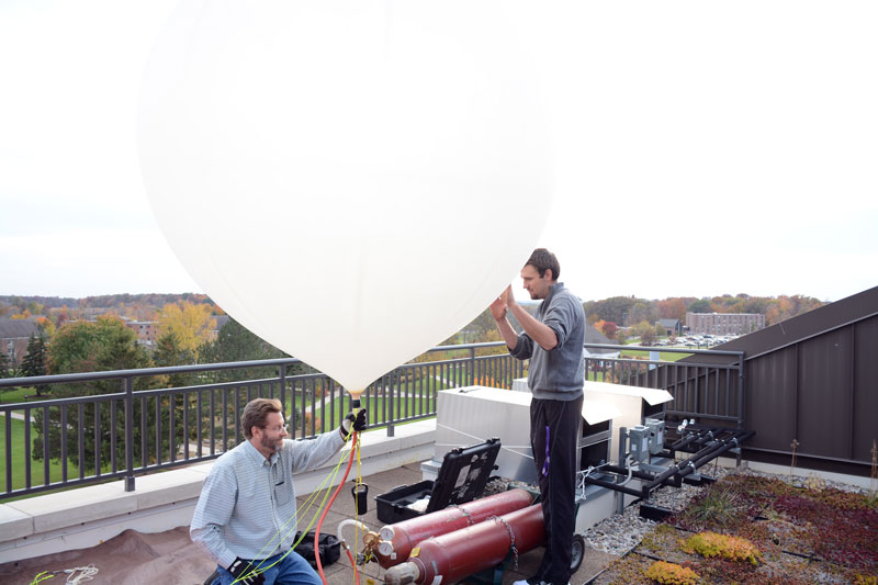 Two engineering majors working on Euler roof inflating a weather balloon