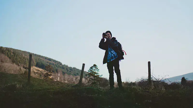 Male student taking a picture while on a hill in Ireland