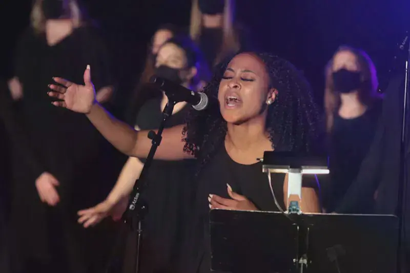 A student holding out her hand in worship while leading the Gospel Choir