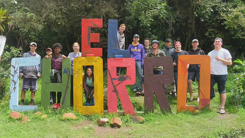 A group of students standing behind a brightly colored El Chorro sign