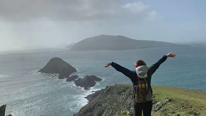 Female student at Slea Head Ireland raising her arms in praise