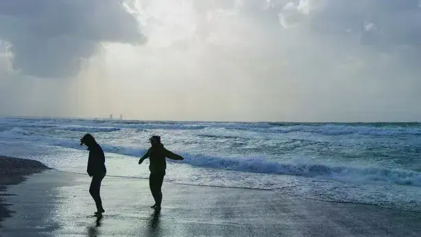 Two silhouetted students walking on the beach.