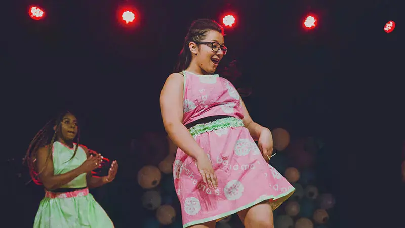 A student in a pink dress dancing at Mosaic Night