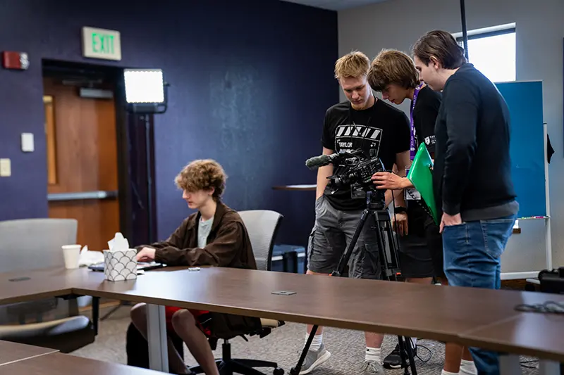 A group of students gathered around a video camera
