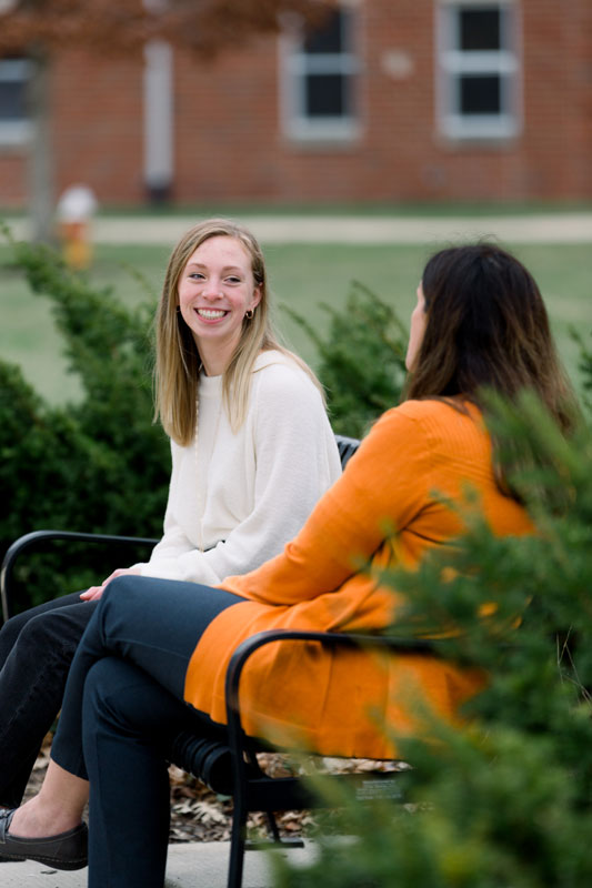 two Psychology students talking on an outdoor bench