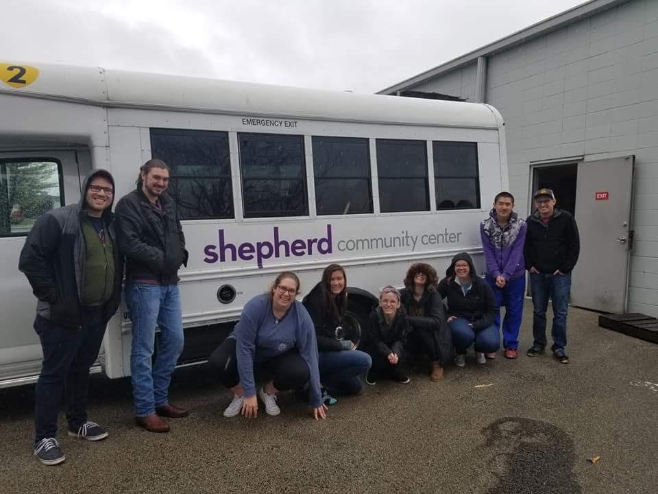 A group of students posing in front of a community center bus