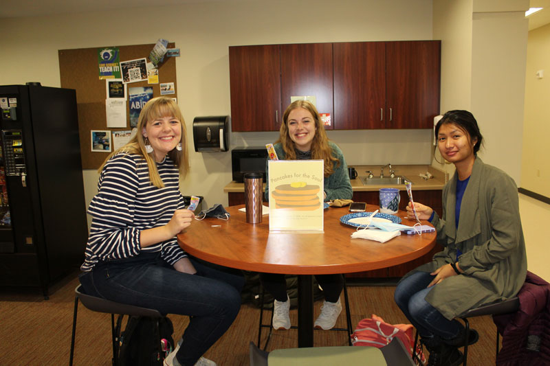 Three female students sitting at a table in the Education Department