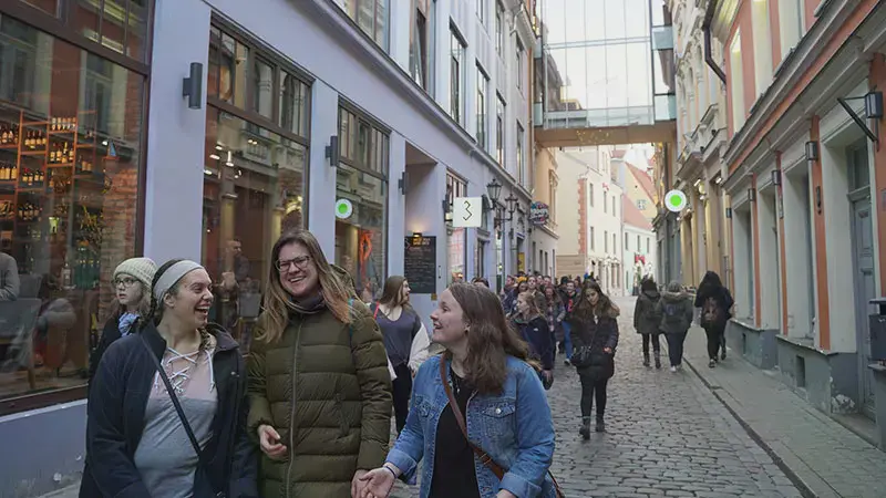Three female students laughing on a street in Latvia