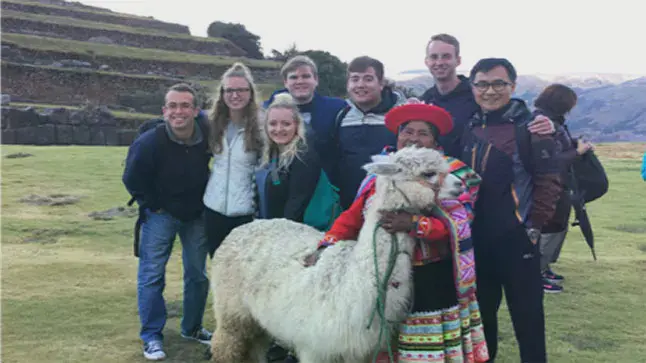 Taylor students and local woman gathered around a llama
