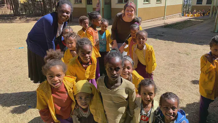 Taylor student poses with children while on a missions trip