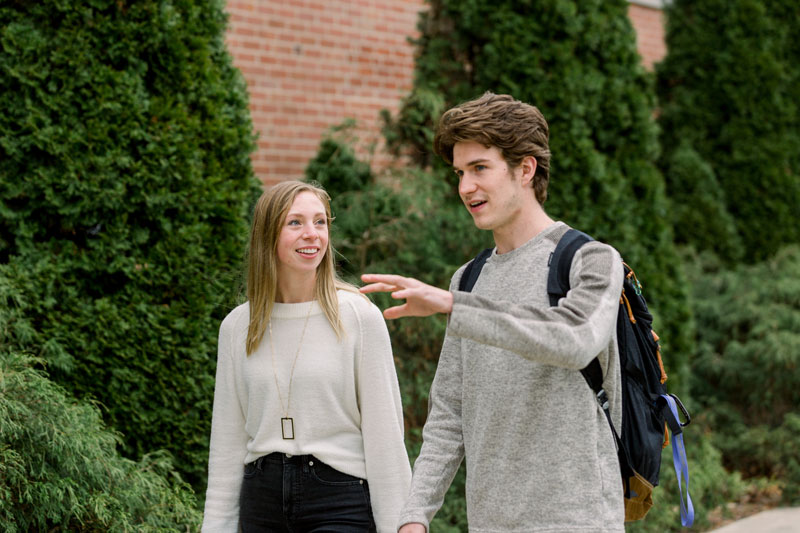 Two students talking and walking on campus