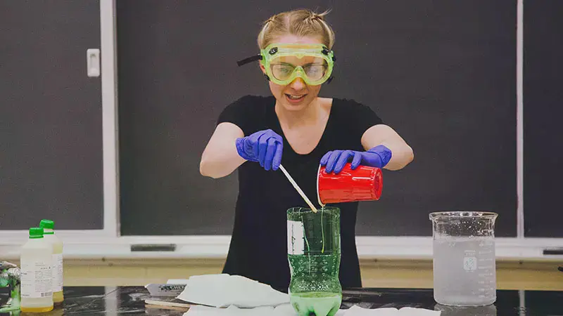 Taylor Chemistry student pouring liquid into a 2-liter bottle