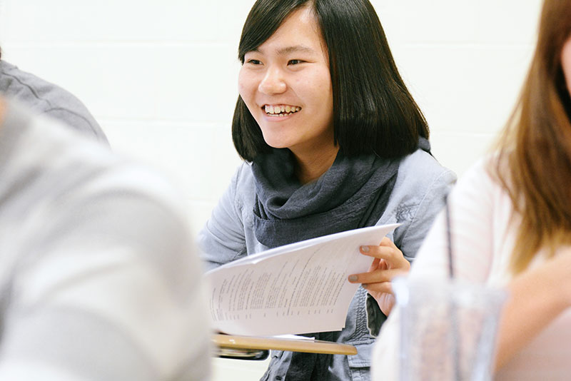 smiling student holding paper in class