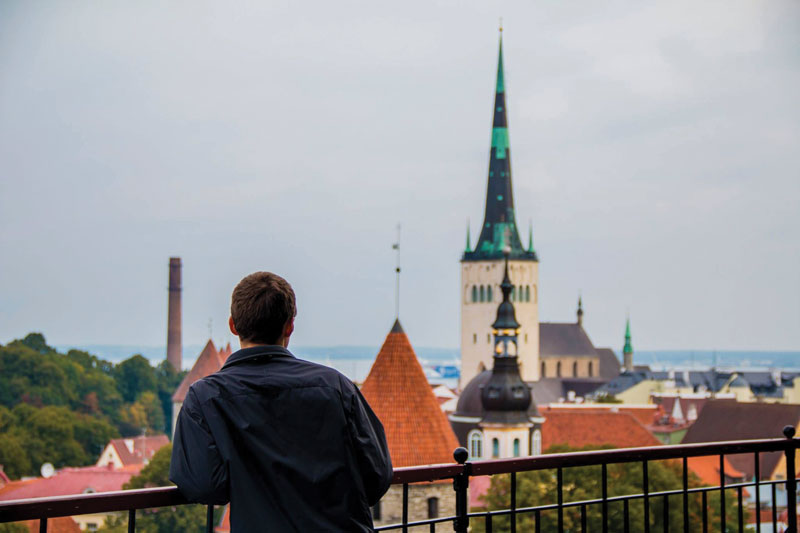 Marketing major student leaning on railing overlooking a cityscape with a steeple