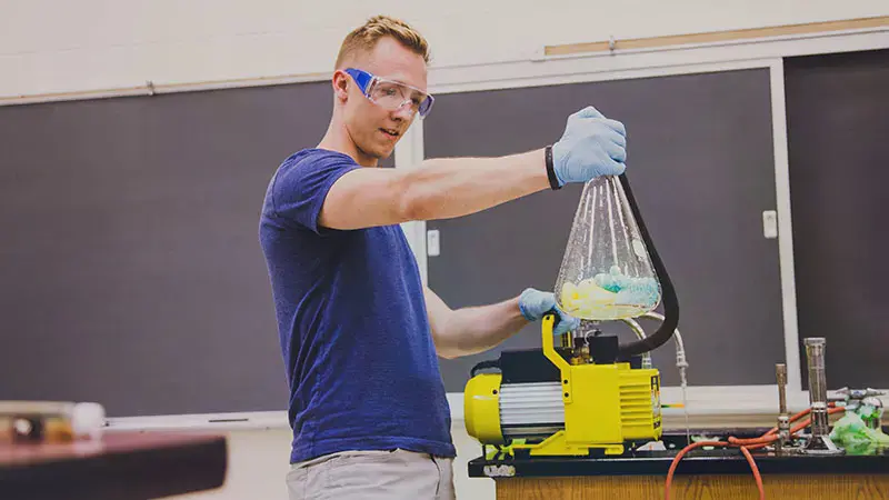 Taylor student holding a flask above a heating element