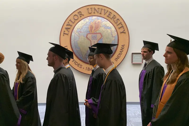 graduates walking past Taylor's presidential seal