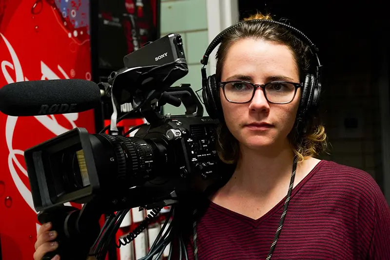 female student holding film camera wearing headphones