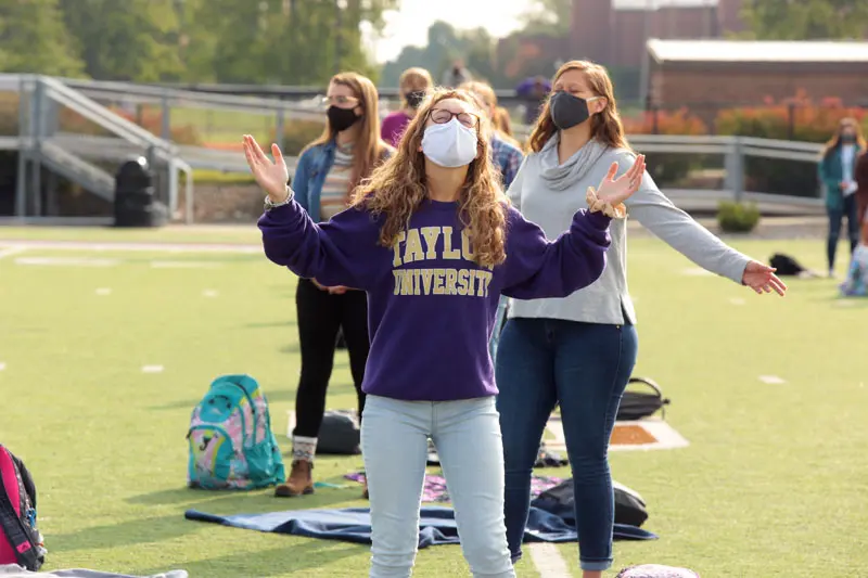 Taylor students worshipping on the football field