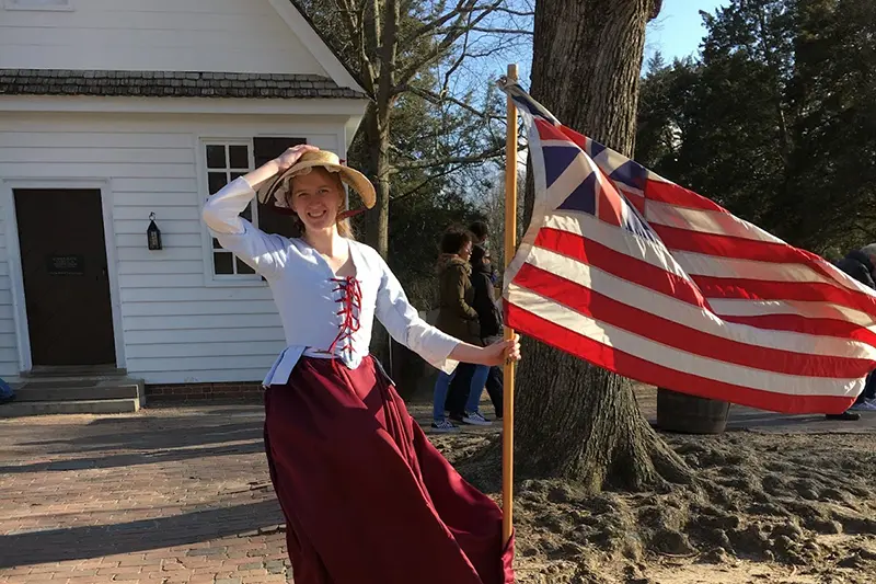 Victoria Koro in Colonial dress holding a flag