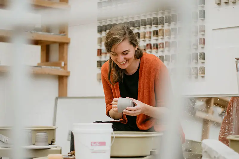 Student making ceramics and smiling