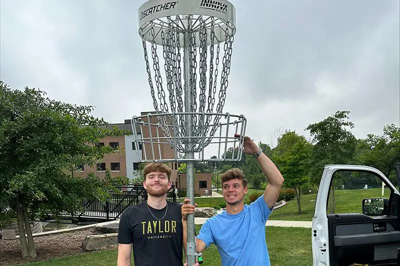 Students next to a disc golf basket