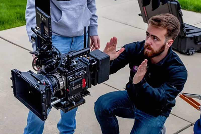 Student lining up shot with a video camera outside