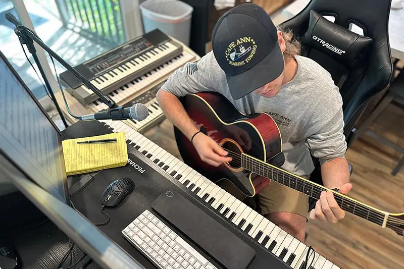 Student with guitar at a computer