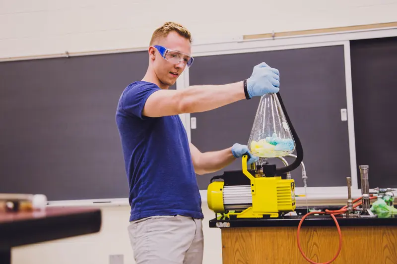 Student holding a flask over a burner