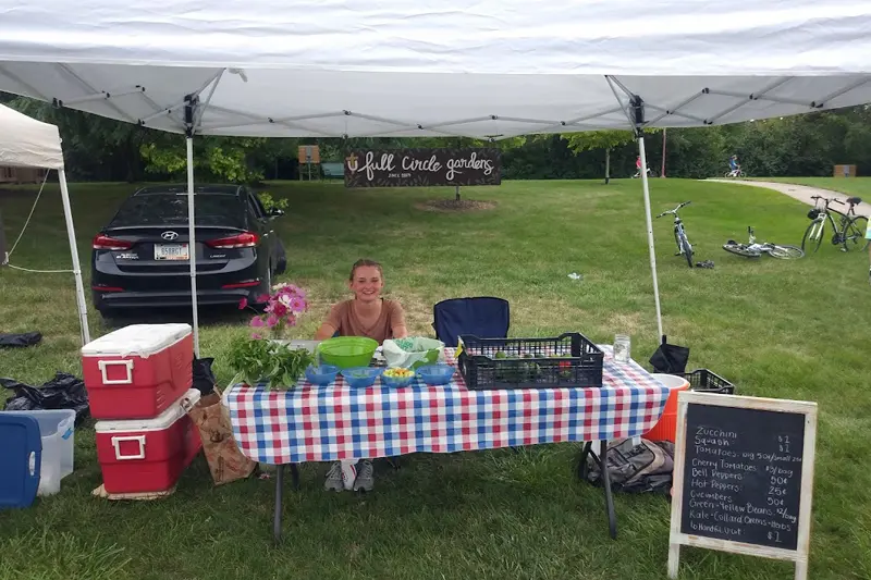 student selling organic produce at a farmer's market